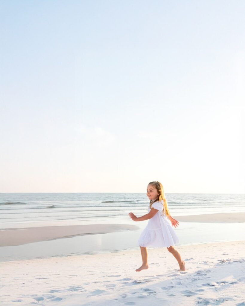 Young girl running along the shoreline during a 30A extended family beach photography session.