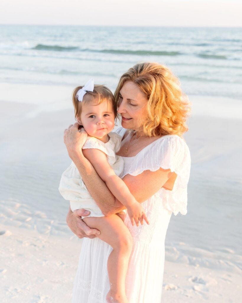 Grandmother holding her young granddaughter on the beach during a 30A extended family photography session.
