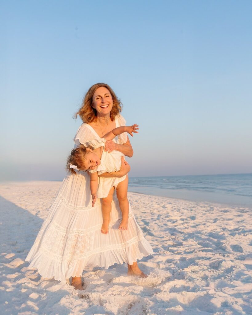 Grandmother holding her granddaughter and smiling on the beach during a 30A extended family photography session.