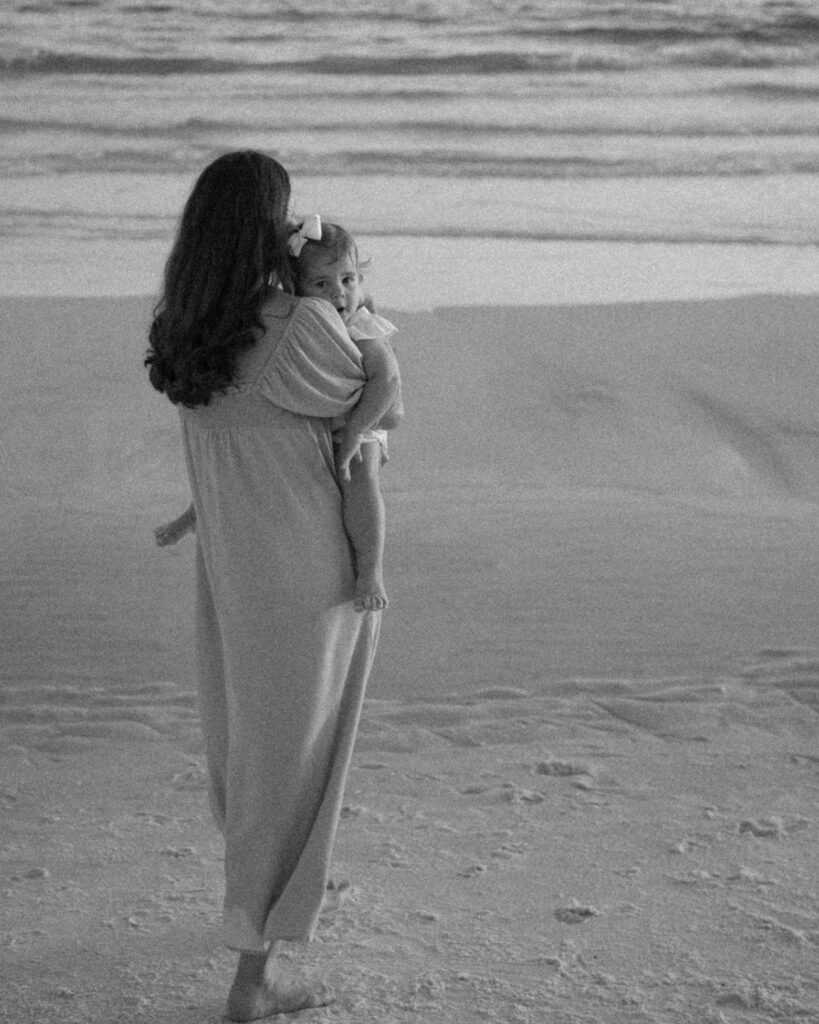 Mother holding her baby near the ocean during a black and white 30A beach family photography session.