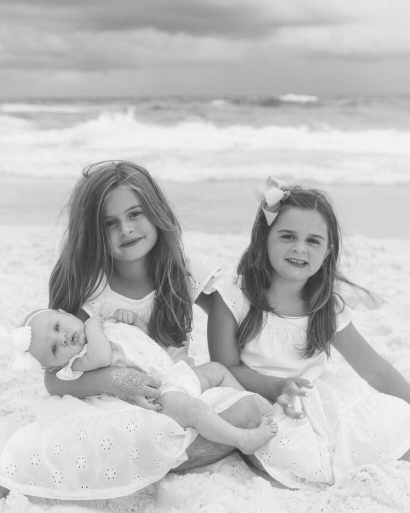 Sisters sitting together on the beach during a family session in Destin Florida