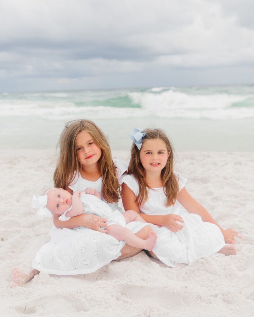 Sisters sitting together on the beach during a family session in Destin Florida