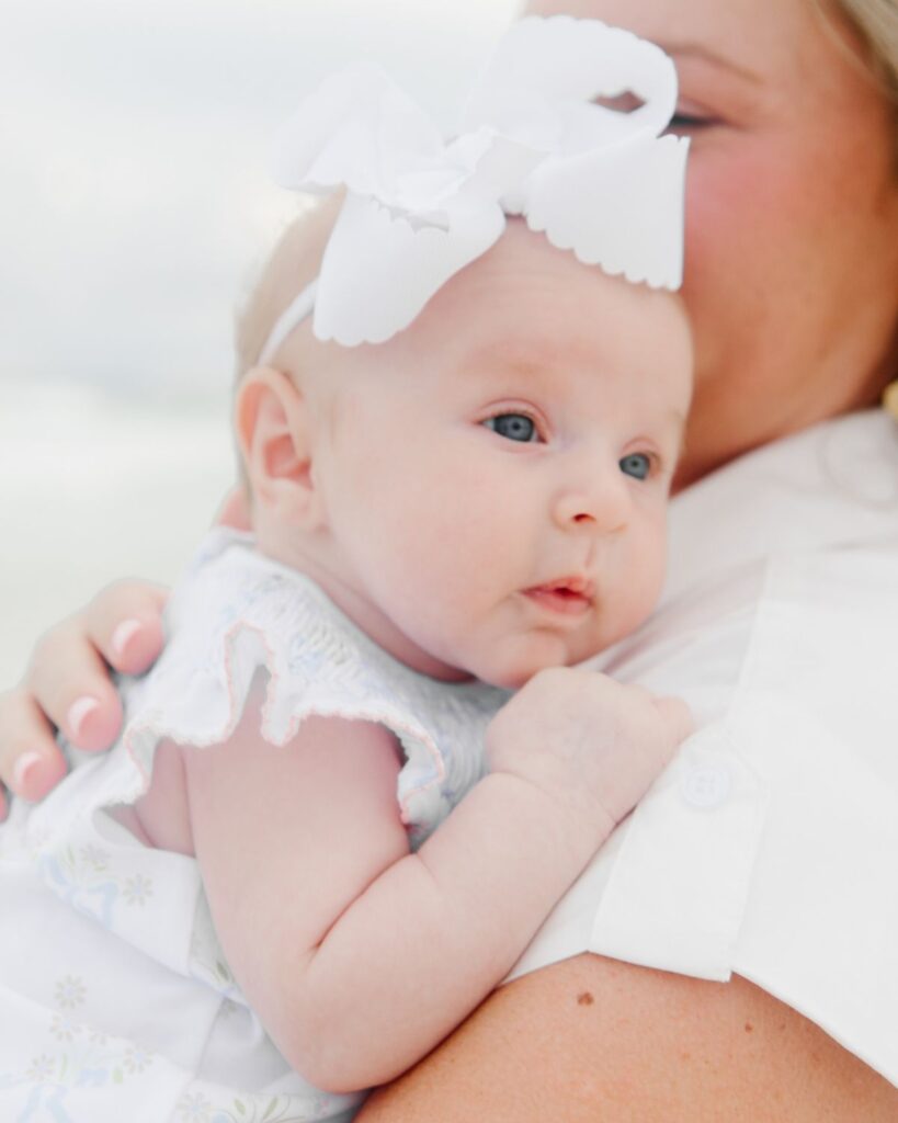 Mom cuddling her newborn baby girl on the beach in Destin Florida