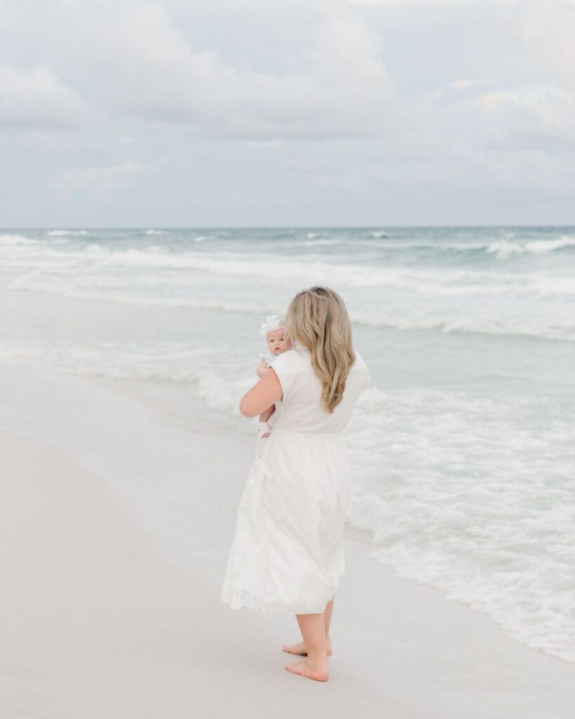 Mom cuddling her newborn baby girl on the beach in Destin Florida