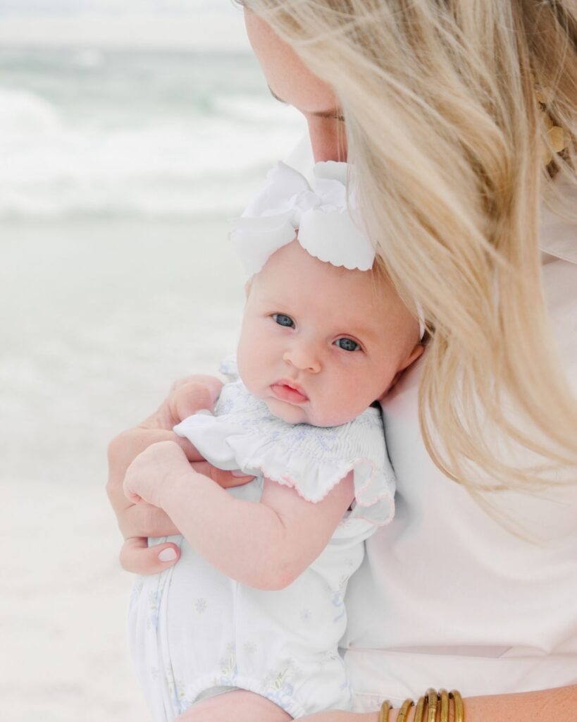 Mother holding her newborn baby girl during a beach family session in Destin Florida