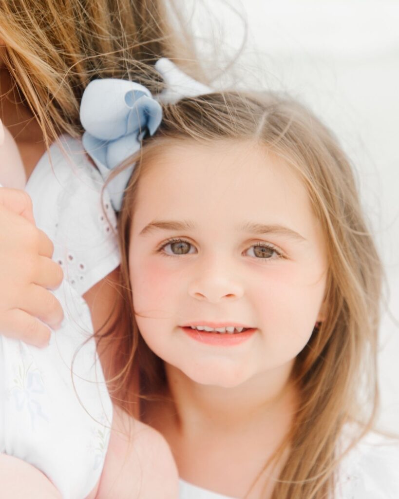 Sisters holding their newborn baby sister during a beach family session in Destin Florida