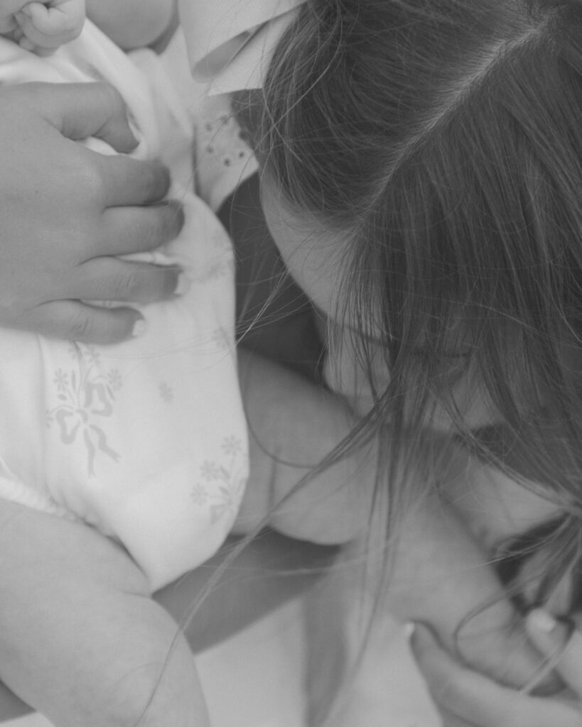 Sisters holding their newborn baby sister during a beach family session in Destin Florida