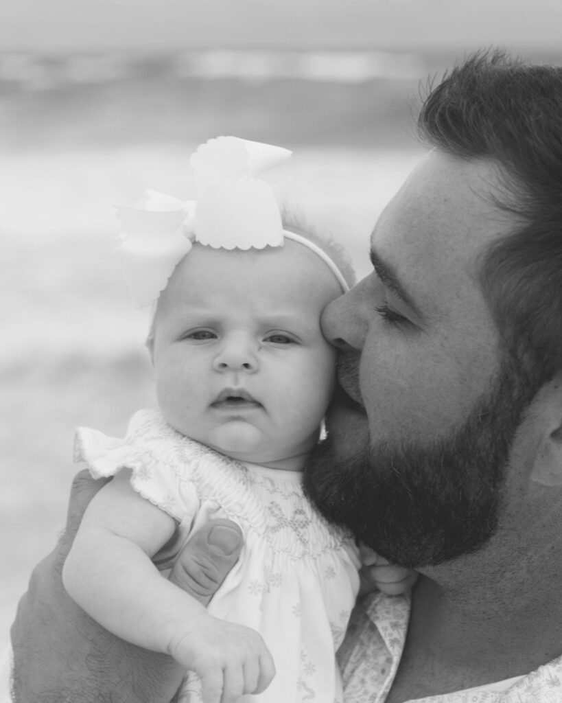 Father holding newborn baby girl during a beach family session in Destin Florida