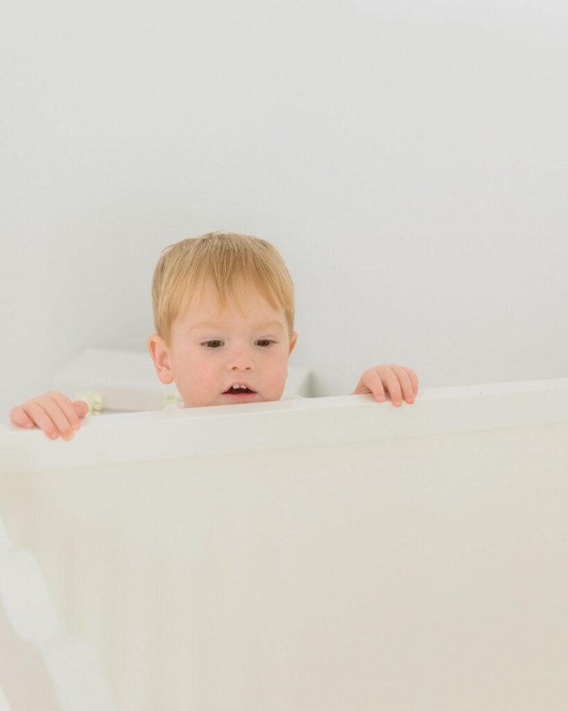 Toddler sibling holding newborn during an in-home lifestyle newborn session in Santa Rosa Beach Florida