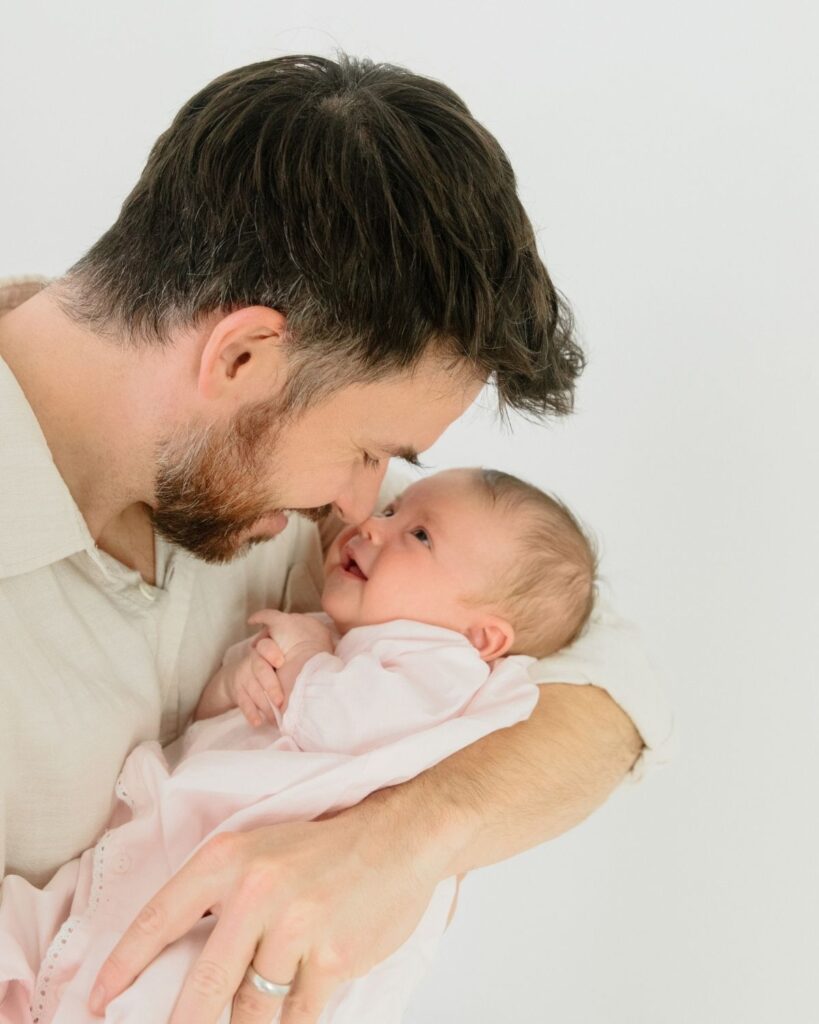 Father holding newborn during an in-home lifestyle newborn session in Santa Rosa Beach Florida