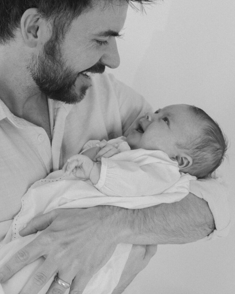 Father holding newborn during an in-home lifestyle newborn session in Santa Rosa Beach Florida