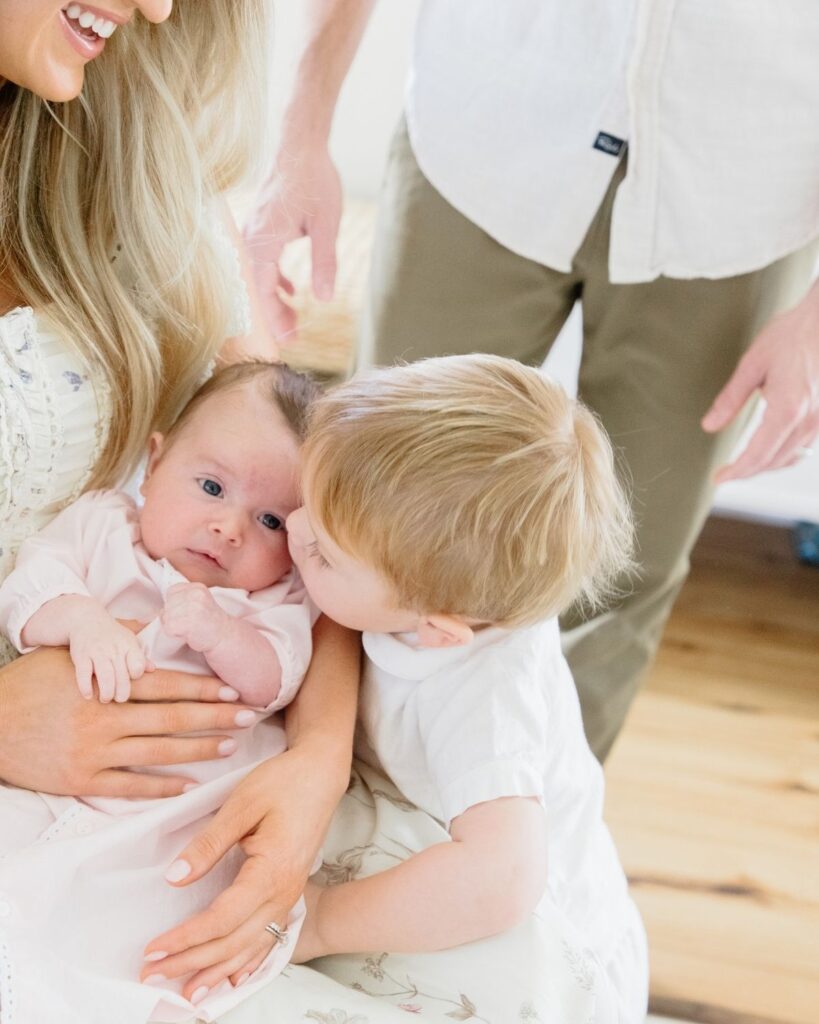 Toddler sibling holding newborn during an in-home lifestyle newborn session in Santa Rosa Beach Florida