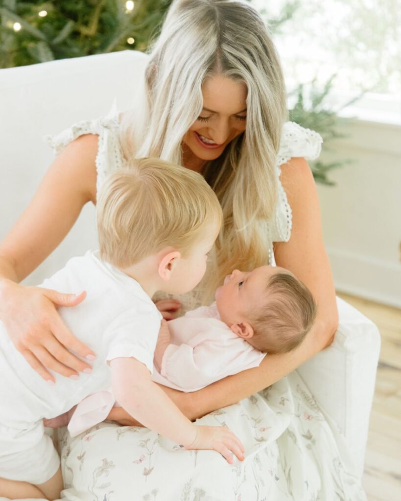 Toddler sibling holding newborn during an in-home lifestyle newborn session in Santa Rosa Beach Florida