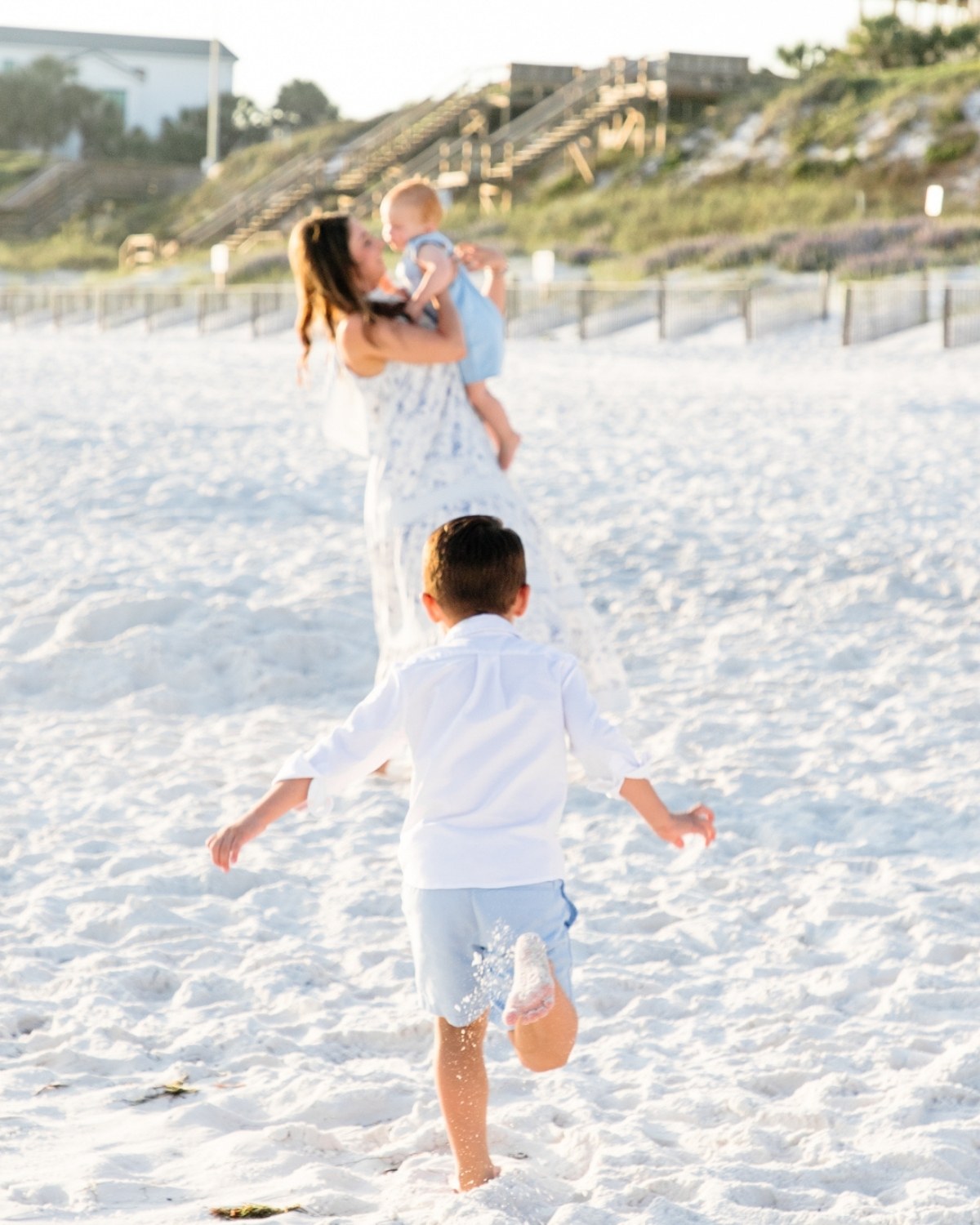 Young boy running toward his mother holding a baby during a 30A extended family photography session.