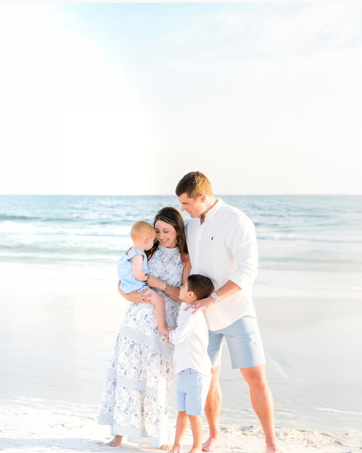 Family of four standing on the beach with seagulls flying overhead during a 30A extended family photography session.