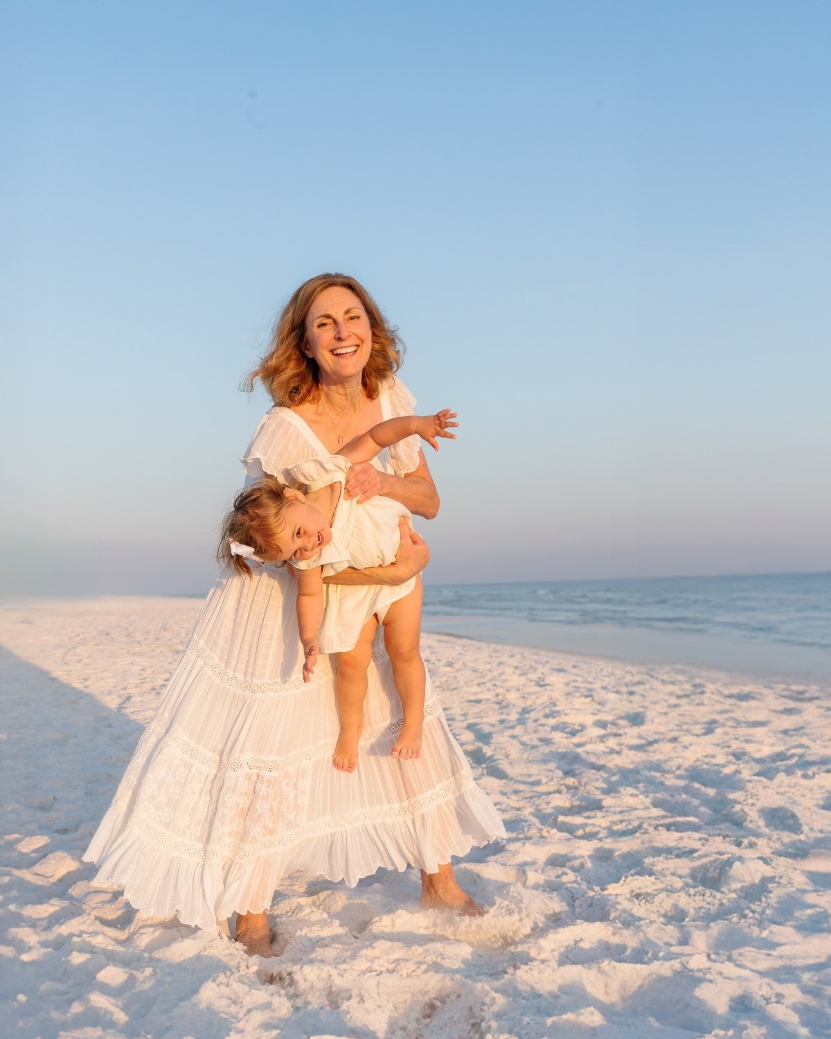 Grandmother holding her granddaughter and smiling on the beach during a 30A extended family photography session.