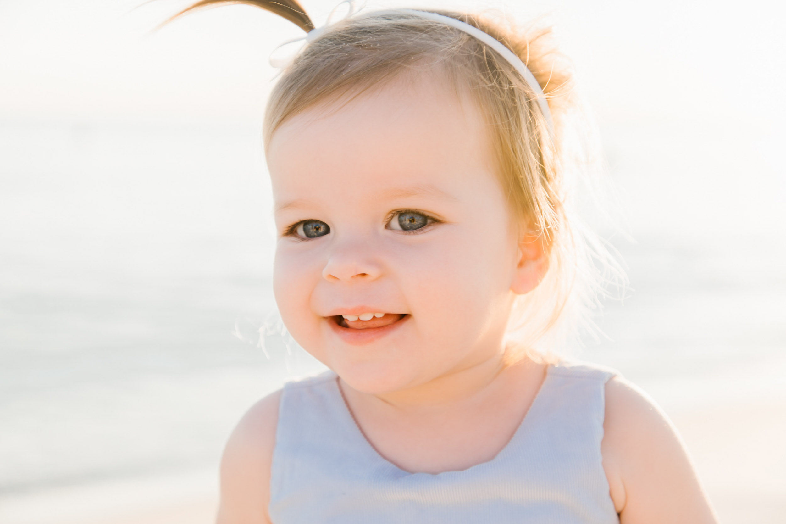 Baby girl looking toward camera at golden hour during a signature family session in Inlet Beach Rosemary Beach Florida on 30A