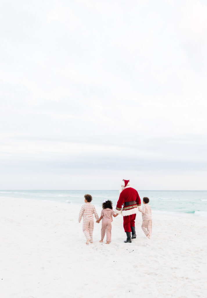 Santa walking with children on the beach during a 30A Santa by the Sea session